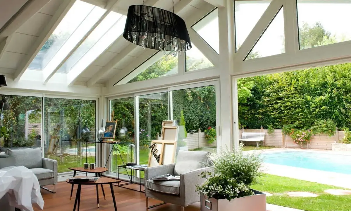 Plan de véranda à faire soi-même : une pièce lumineuse avec vue sur piscine, mobilier confortable et espace artistique.