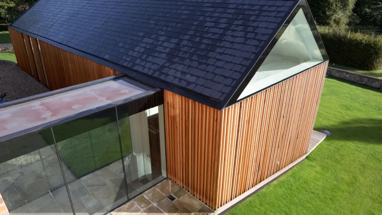 Vue aérienne d'un agrandissement maison sur le côté, avec bardage bois, toit en ardoises et extension vitrée.