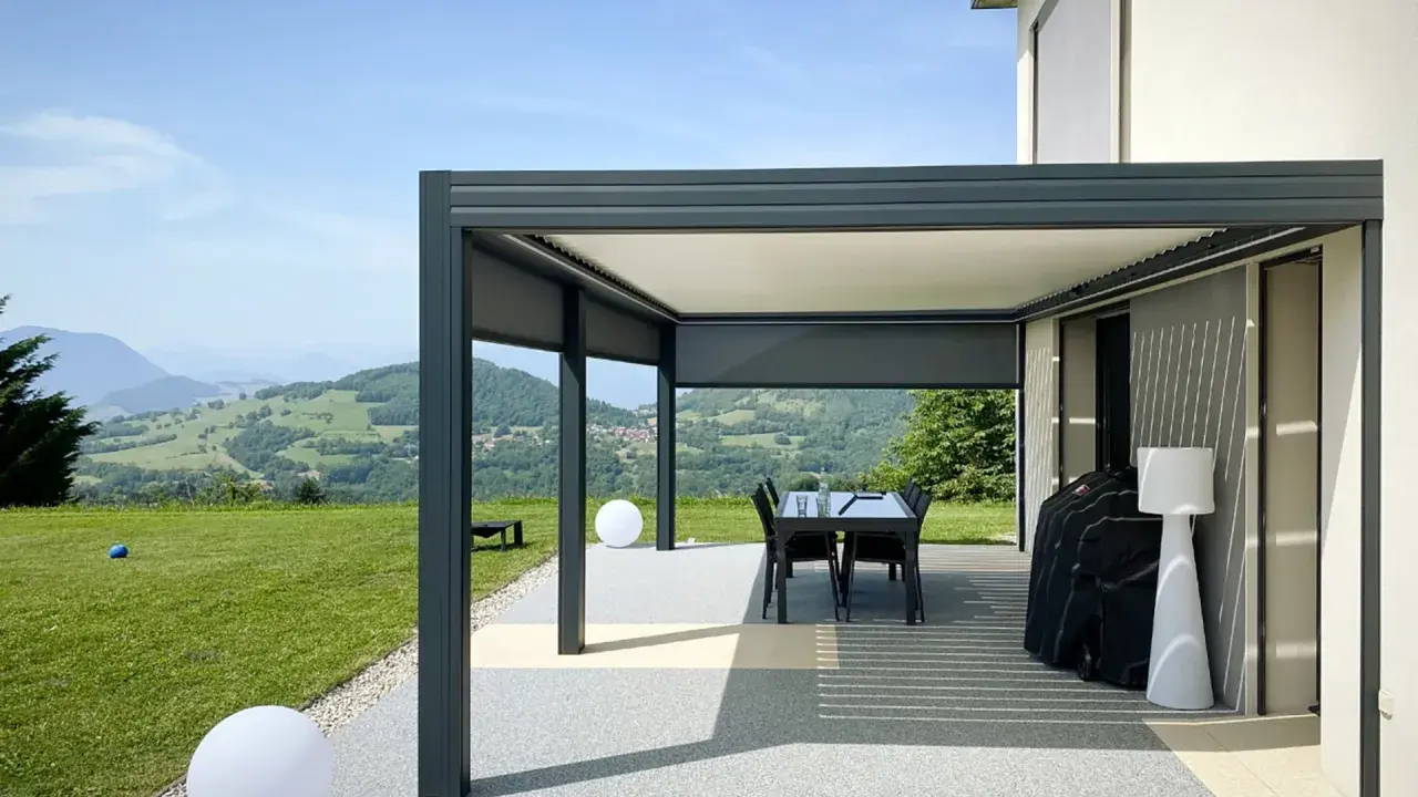 Pergola bioclimatique moderne face à un paysage vallonné. Le vent fort fait onduler les lames du toit, créant des jeux d'ombre et de lumière.