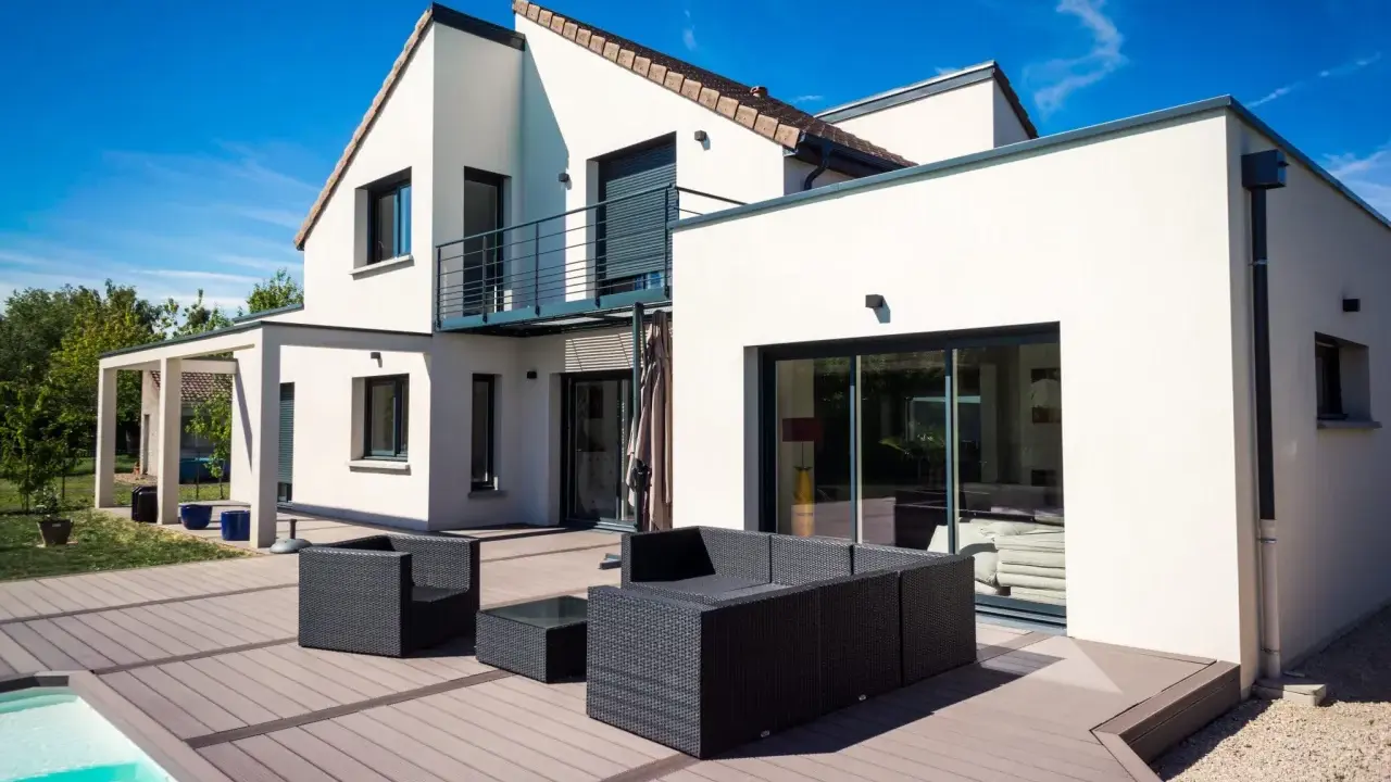 Une maison moderne avec une extension spacieuse, une terrasse en bois et une piscine. L'ensemble évoque une transformation réussie : extension maison avant après.