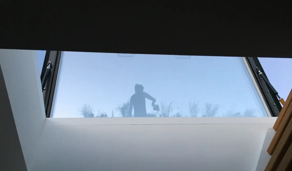Silhouette d'une personne arrosant des plantes à travers un puit de lumière panneau sandwich.