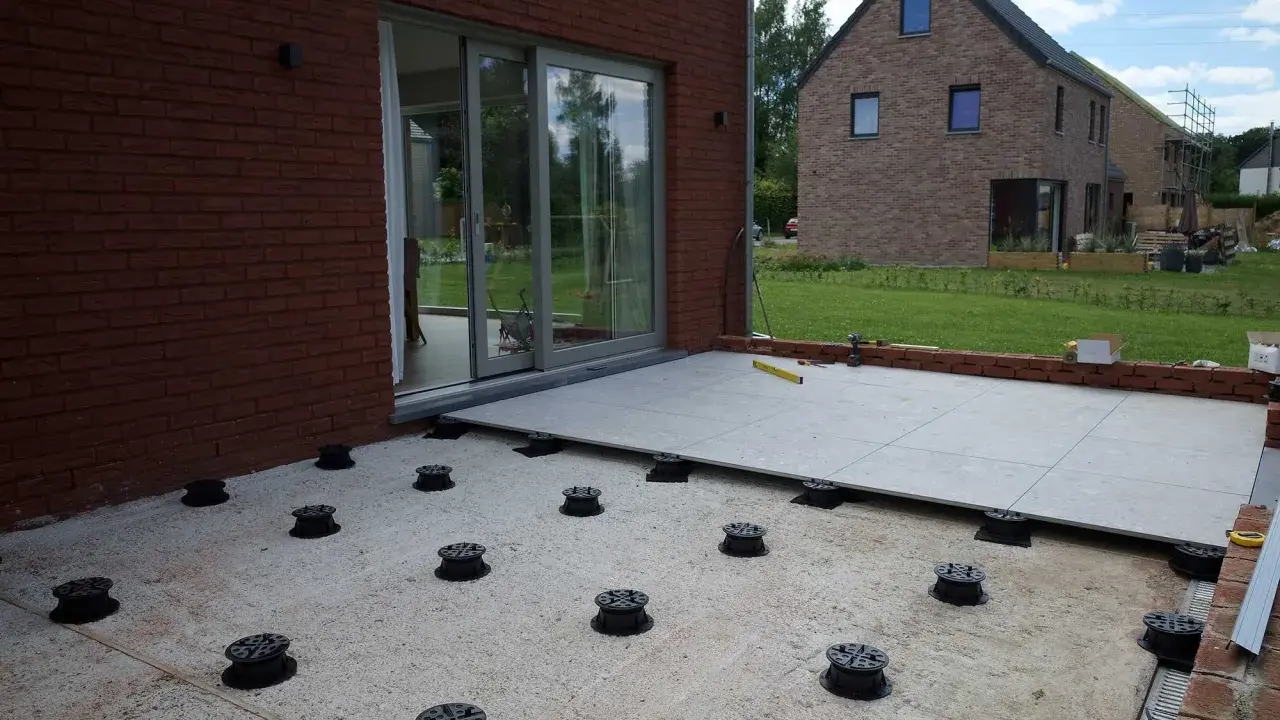 Installation de la dalle pour veranda sur des plots réglables. Le sol est en cours d'aménagement.