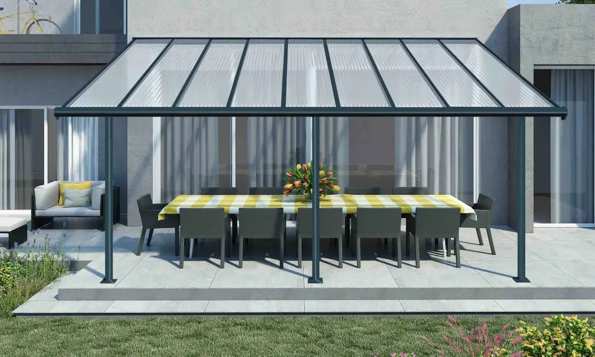 Une pergola canisse protège une table dressée et des fauteuils de la pluie, créant un espace extérieur accueillant.