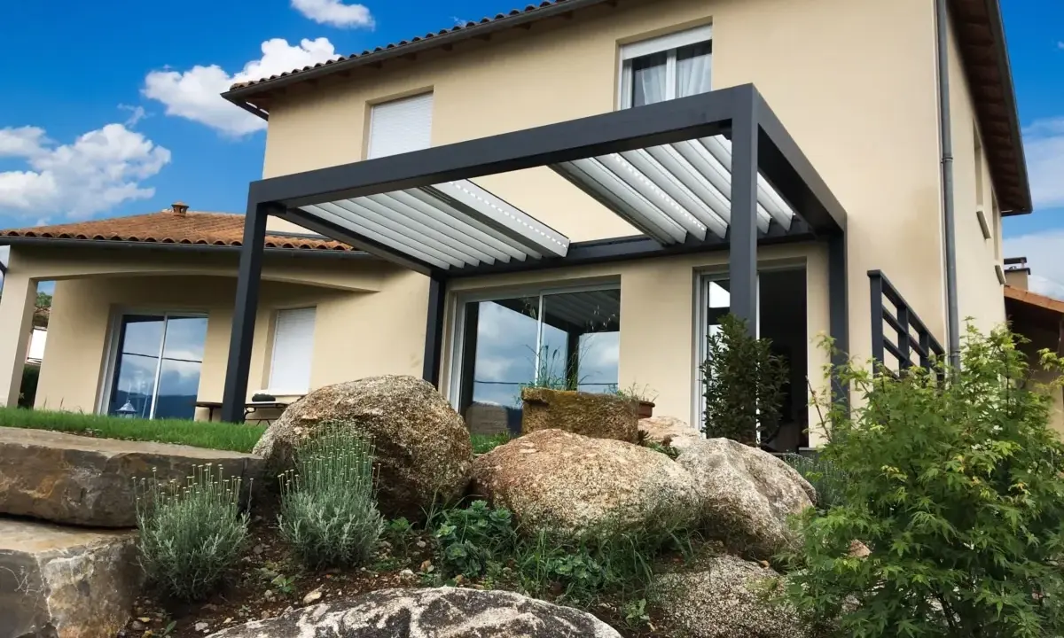 Pergola moderne sur terrasse avec vue sur une maison et un jardin rocheux.