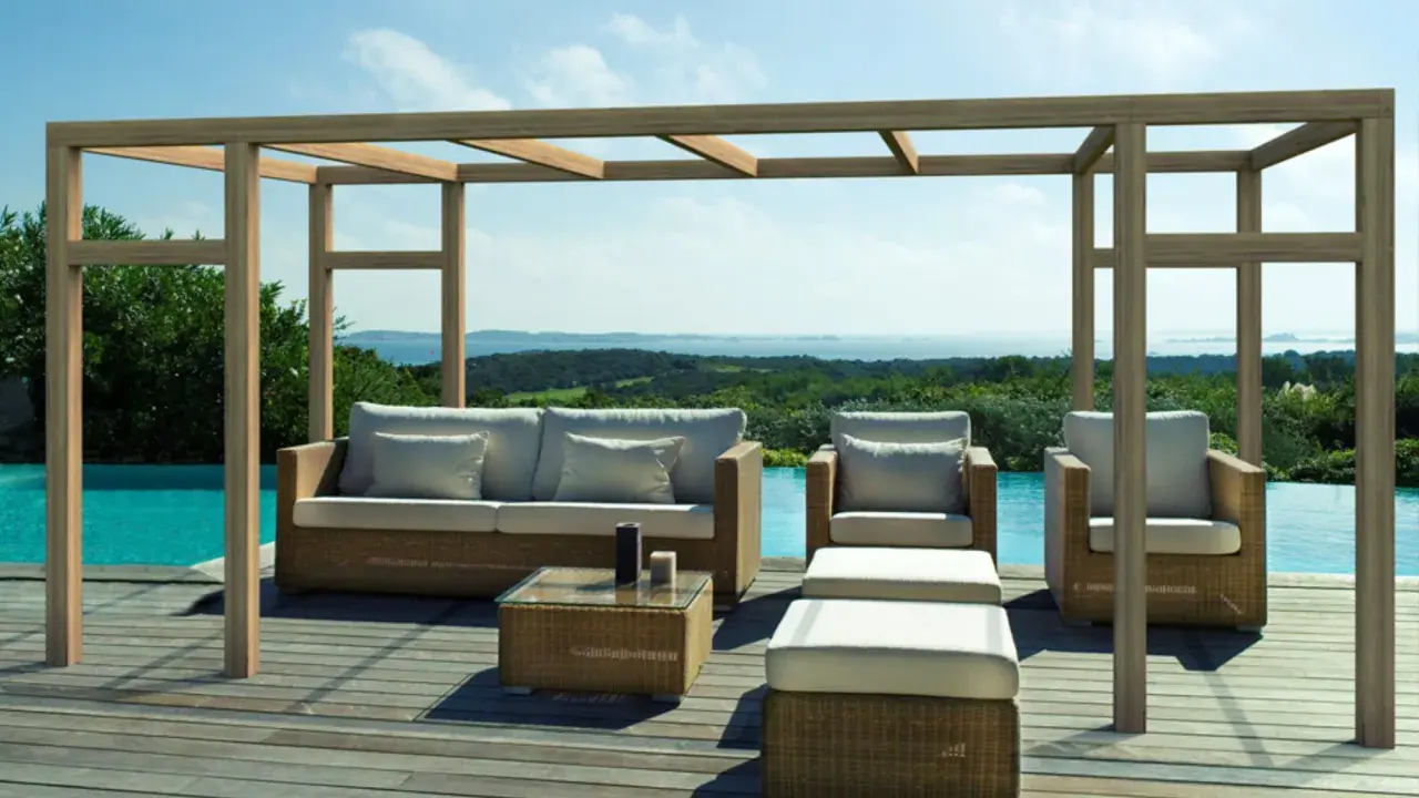 Salon extérieur avec mobilier en rotin sous une pergola en bois. La hauteur de la pergola en bois offre une ombre agréable sur la terrasse en bois, près de la piscine.