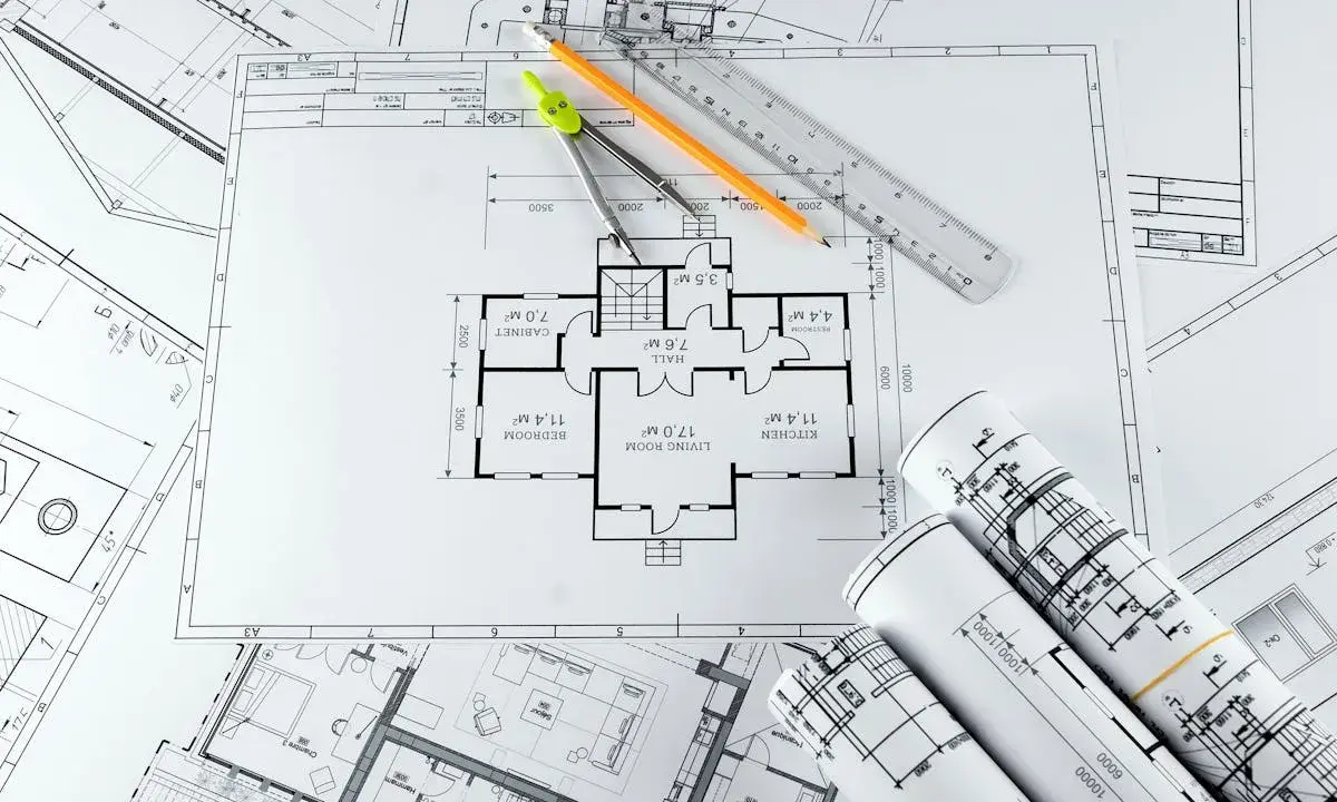 Plans d'architecte, compas, crayon et règle pour savoir comment faire une extension de maison pas chère.
