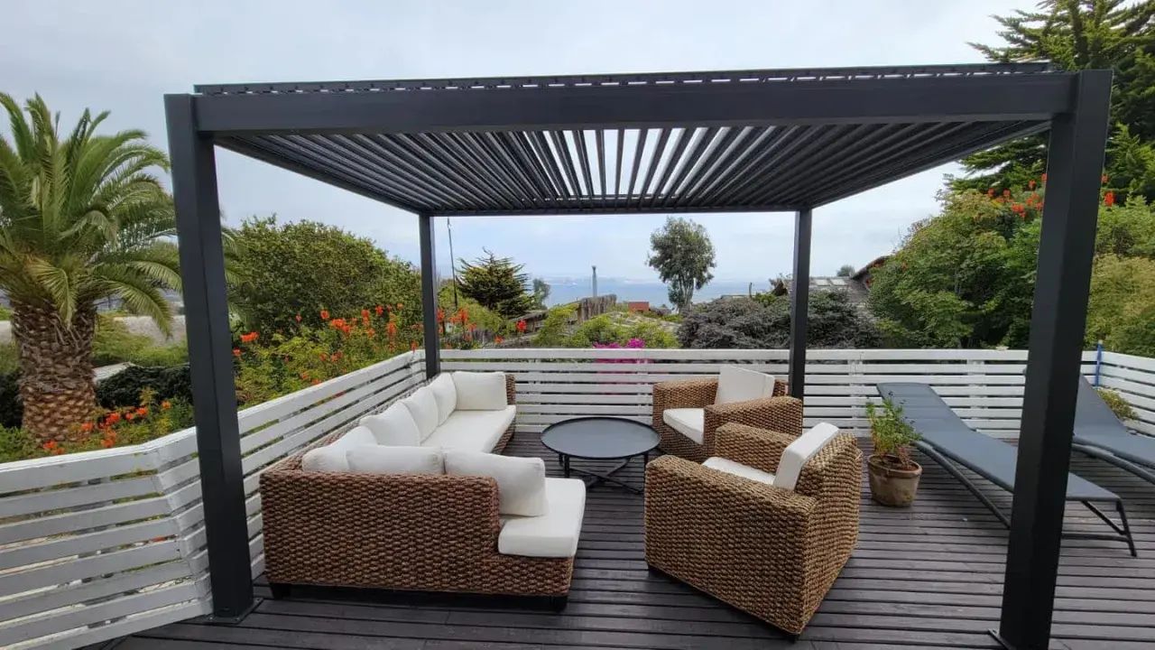 Un salon d'extérieur confortable sous une pergola sur toit terrasse, avec vue sur la mer.
