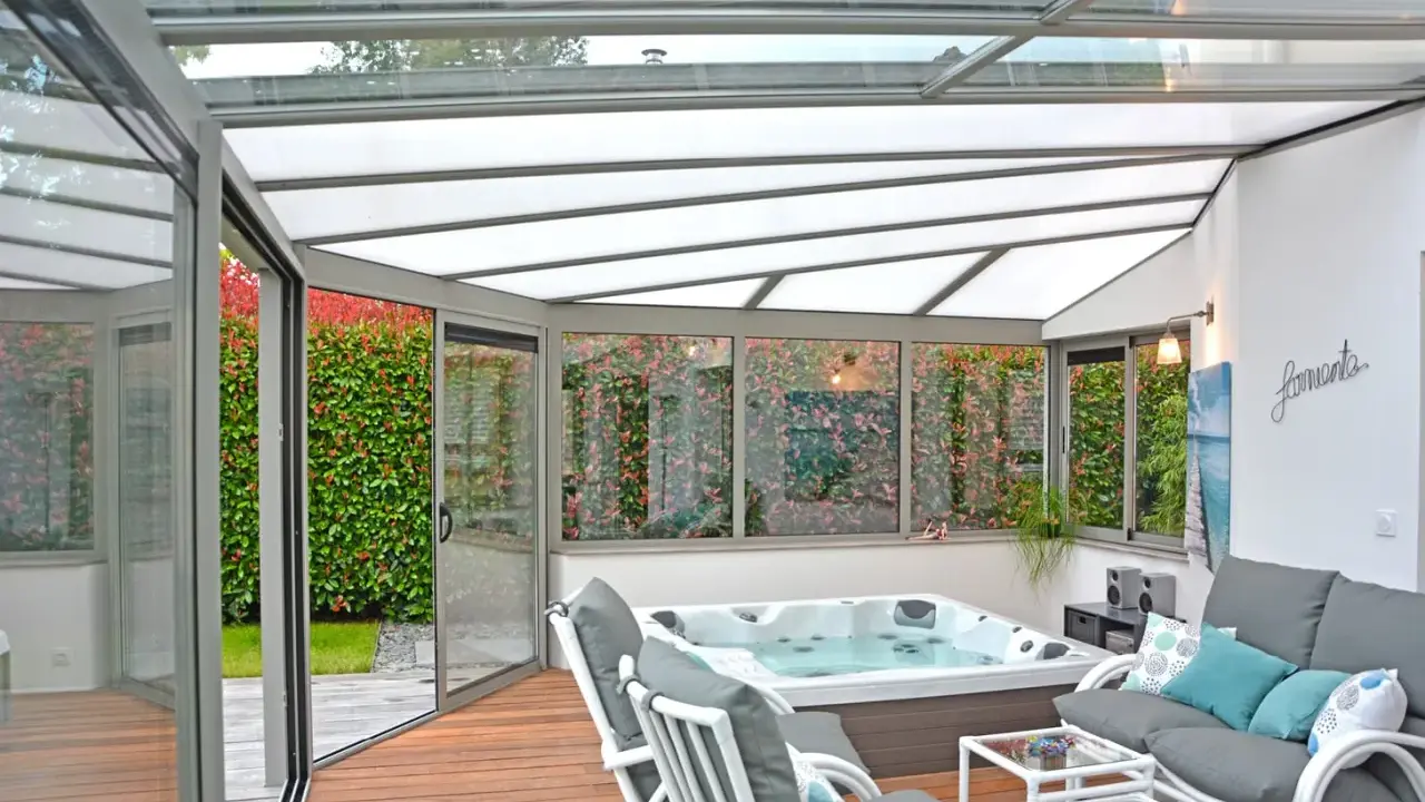 Une **fenêtre de toit veranda** lumineuse abrite un jacuzzi et un coin salon confortable, avec vue sur un jardin luxuriant.