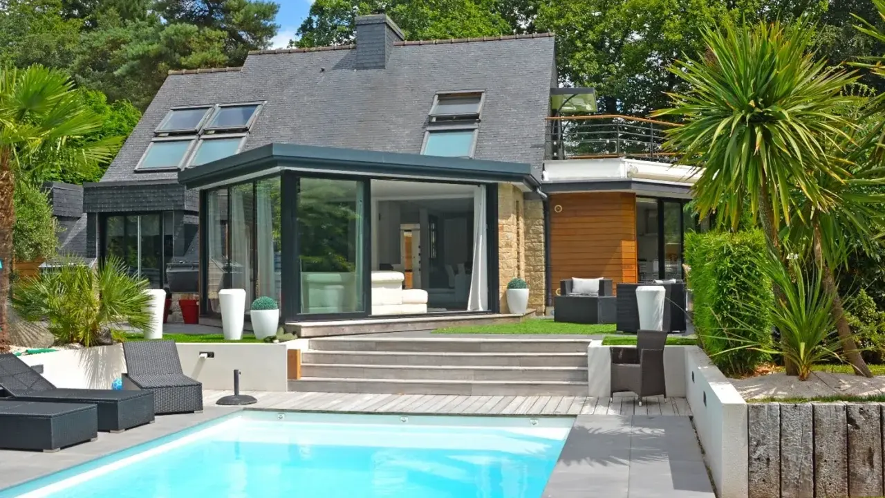 Maison moderne avec véranda et piscine. Pensez à comment déclarer une véranda aux impôts pour optimiser votre situation.