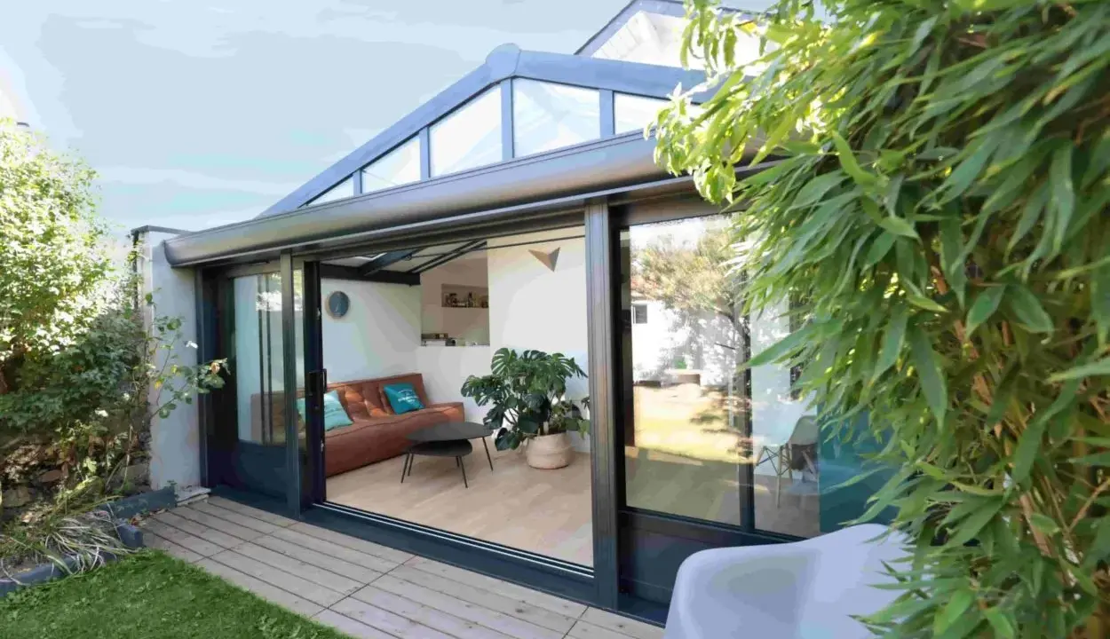 Une véranda sur terrasse sans fondation, avec un salon confortable et une vue sur le jardin verdoyant.