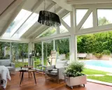 Plan de véranda à faire soi-même : une pièce lumineuse avec vue sur piscine, mobilier confortable et espace artistique.