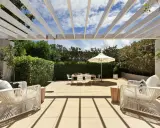 Terrasse couverte avec pergola blanche, mobilier de jardin blanc, table et parasol. Un espace extérieur aménagé, peut-être pour fermer une terrasse couverte sans autorisation.