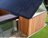 Vue aérienne d'un agrandissement maison sur le côté, avec bardage bois, toit en ardoises et extension vitrée.