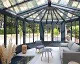 Une extension veranda moderne baignée de lumière, avec un salon confortable et une vue imprenable sur le jardin verdoyant.
