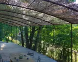 Vue d'une terrasse en bois sous une pergola recouverte de canisse. Le sens de pose de canisse sur pergola offre une ombre naturelle et agréable.