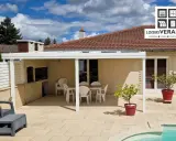 Un fabricant de pergolas a installé cette belle terrasse avec mobilier de jardin, barbecue et piscine.