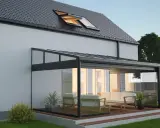 Une élégante veranda hexagonale en verre et métal, avec un salon confortable, s'intègre parfaitement à une maison moderne.