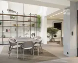 Une salle à manger moderne et lumineuse, avec une grande étagère murale, une table et des chaises, et une cheminée design. Cette **petite extension de maison** est un espace de vie accueillant.