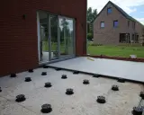 Installation de la dalle pour veranda sur des plots réglables. Le sol est en cours d'aménagement.
