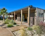 Maison moderne avec une extension toiture terrasse en bois, entourée d'un jardin paysager et d'une terrasse en bois.