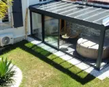 Une **veranda tuile** moderne avec jacuzzi et fauteuils, entourée d'un jardin verdoyant et d'une palme luxuriante.