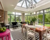 Une élégante verrière d'extension de maison baigne de lumière cette salle à manger, offrant une vue imprenable sur le jardin verdoyant.