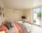 Chambre lumineuse d'une extension de maison, avec un lit confortable, une télévision et un accès direct à une terrasse extérieure.