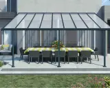 Une pergola canisse protège une table dressée et des fauteuils de la pluie, créant un espace extérieur accueillant.