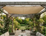 Pente pergola en bois avec roses grimpantes et glycines, offrant un coin salon extérieur paisible.