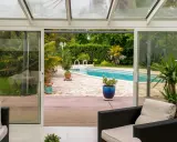 Une extension vitrée moderne s'ouvre sur une piscine et un jardin luxuriant, invitant à la détente.