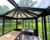 Intérieur d'une **veranda 2 pans** avec mobilier, sol décoratif et vue sur un jardin verdoyant.