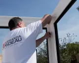 Un ouvrier installe une structure de véranda, remplaçant un ancien surbau béton.
