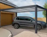 Une voiture grise est garée sous un tva carport moderne, à côté d'un garage.