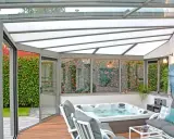 Une **fenêtre de toit veranda** lumineuse abrite un jacuzzi et un coin salon confortable, avec vue sur un jardin luxuriant.