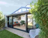 Une véranda sur terrasse sans fondation, avec un salon confortable et une vue sur le jardin verdoyant.