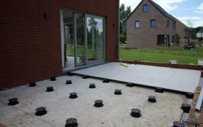 Installation de la dalle pour veranda sur des plots réglables. Le sol est en cours d'aménagement.