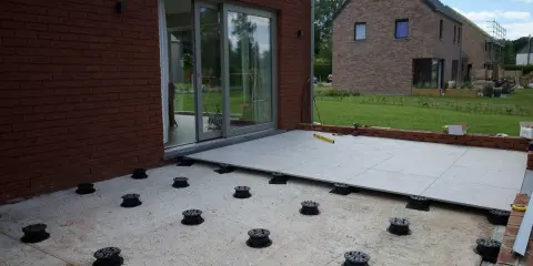 Installation de la dalle pour veranda sur des plots réglables. Le sol est en cours d'aménagement.