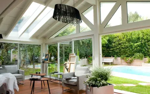 Plan de véranda à faire soi-même : une pièce lumineuse avec vue sur piscine, mobilier confortable et espace artistique.
