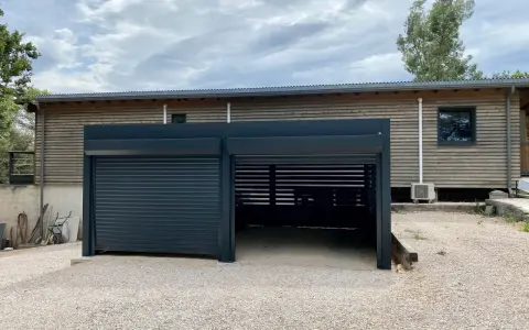Abri voiture moderne avec un volet roulant fermé et une partie ouverte. Faut-il un permis de construire pour un abri voiture ouvert ?