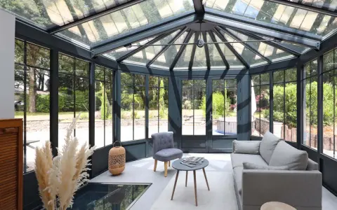 Une extension veranda moderne baignée de lumière, avec un salon confortable et une vue imprenable sur le jardin verdoyant.