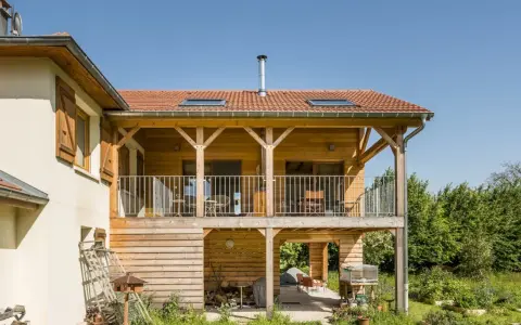 Extension en bois sur pilotis, avec balcon et terrasse aménagée. Une belle intégration architecturale.