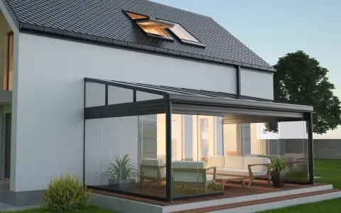 Une élégante veranda hexagonale en verre et métal, avec un salon confortable, s'intègre parfaitement à une maison moderne.