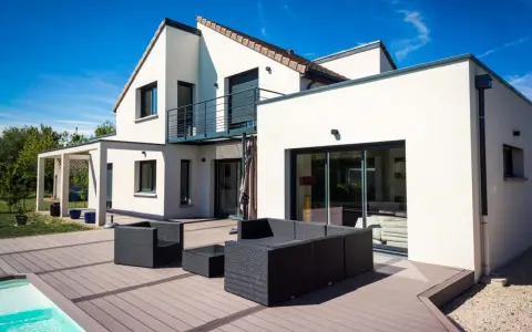 Une maison moderne avec une extension spacieuse, une terrasse en bois et une piscine. L'ensemble évoque une transformation réussie : extension maison avant après.