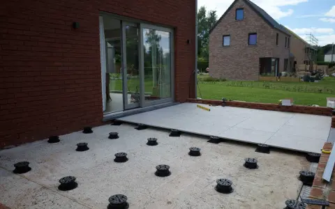 Installation de la dalle pour veranda sur des plots réglables. Le sol est en cours d'aménagement.