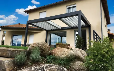 Pergola moderne sur terrasse avec vue sur une maison et un jardin rocheux.