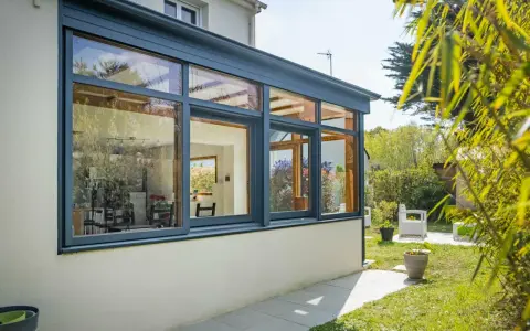 Belle extension cuisine sur jardin, avec de grandes baies vitrées offrant une vue imprenable sur la verdure et le soleil.