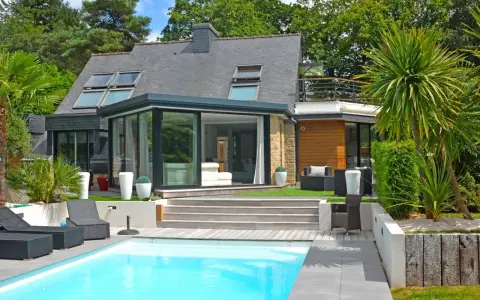 Maison moderne avec véranda et piscine. Pensez à comment déclarer une véranda aux impôts pour optimiser votre situation.