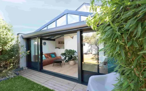 Une véranda sur terrasse sans fondation, avec un salon confortable et une vue sur le jardin verdoyant.