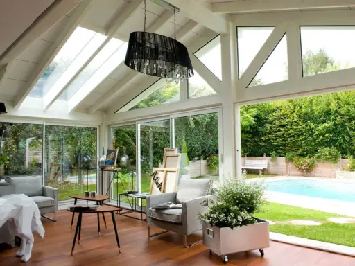 Plan de véranda à faire soi-même : une pièce lumineuse avec vue sur piscine, mobilier confortable et espace artistique.