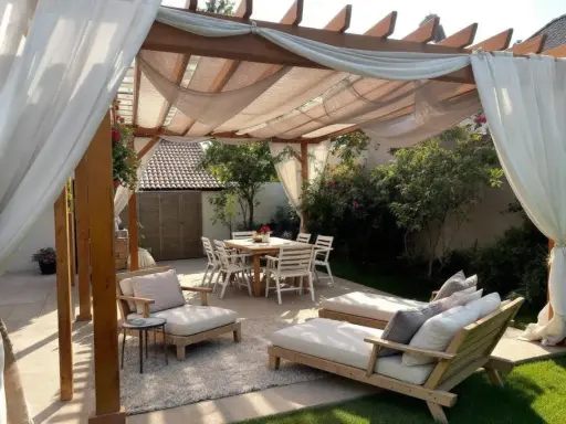Une belle idée pergola jardin avec salon de jardin, chaises et table à manger, le tout sous des voilages légers.